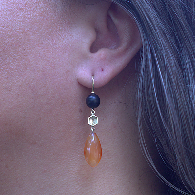 Lange gouden honey oorhaken met matte zwarte Onyx en oranje Carneool en honingraat element. handgemaakt en duurzaam design door Goudsmederij Goedbloed foto op model