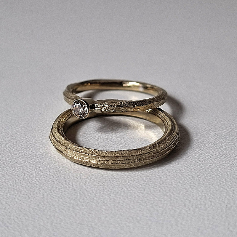 Organische minimalistische luxe Forest trouwringen met de lange textuur van Angelica, de dames ring heeft een bruine diamant solitaire rondomzetting. Handgemaakt bewust design door Goudsmederij Goedbloed