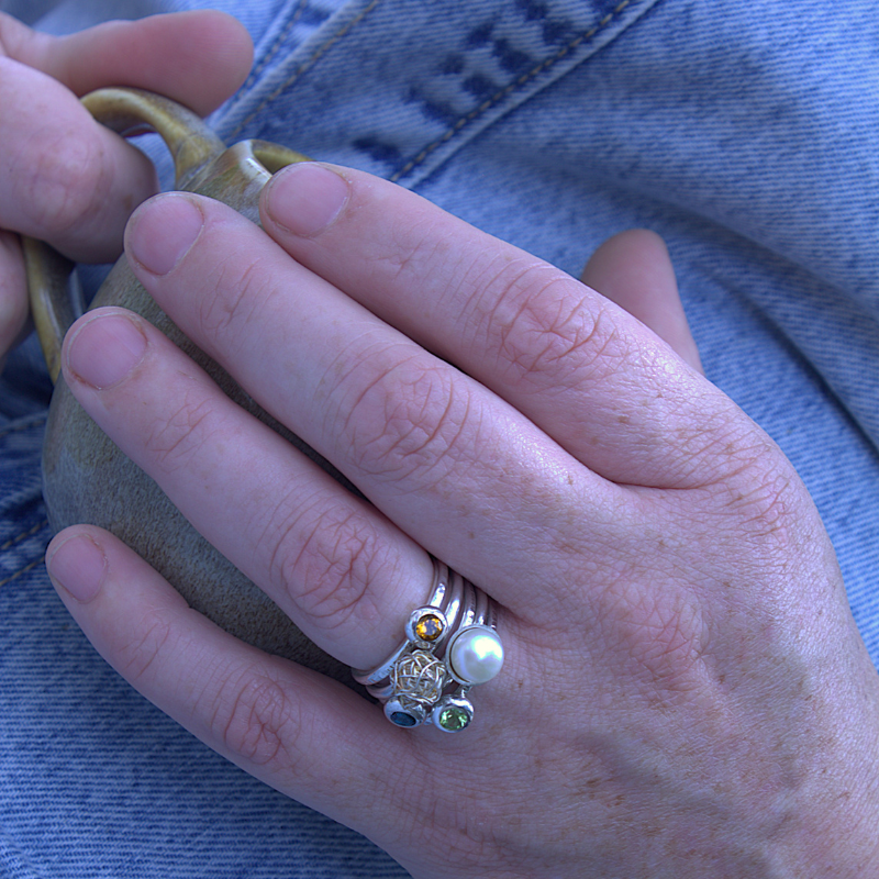 Een setje zilveren aanschuifringen met diverse edelstenen en parels. Handgemaakt door Goudsmederij Goedbloed foto op model