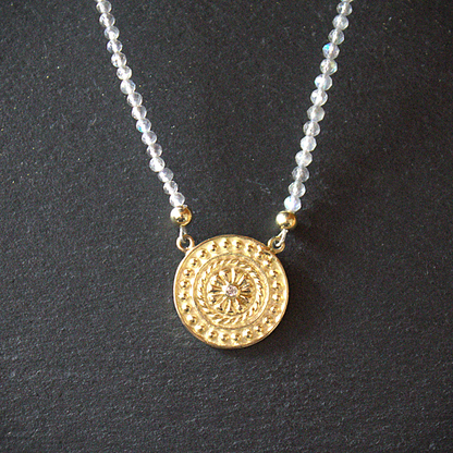 Gouden mandala hanger munt met in het midden een witte diamant;  aan een snoer van gefacetteerde Labradoriet duurzaam en handgemaakt design door Goudsmederij Goedbloed