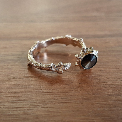 14 karaat gouden open ring, een gouden tak met knop vormt de ring en eindigt met schuine geribbelde kap waarin een unieke gouden Korund is gezet. Handgemaakt door Goudsmederij Goedbloed