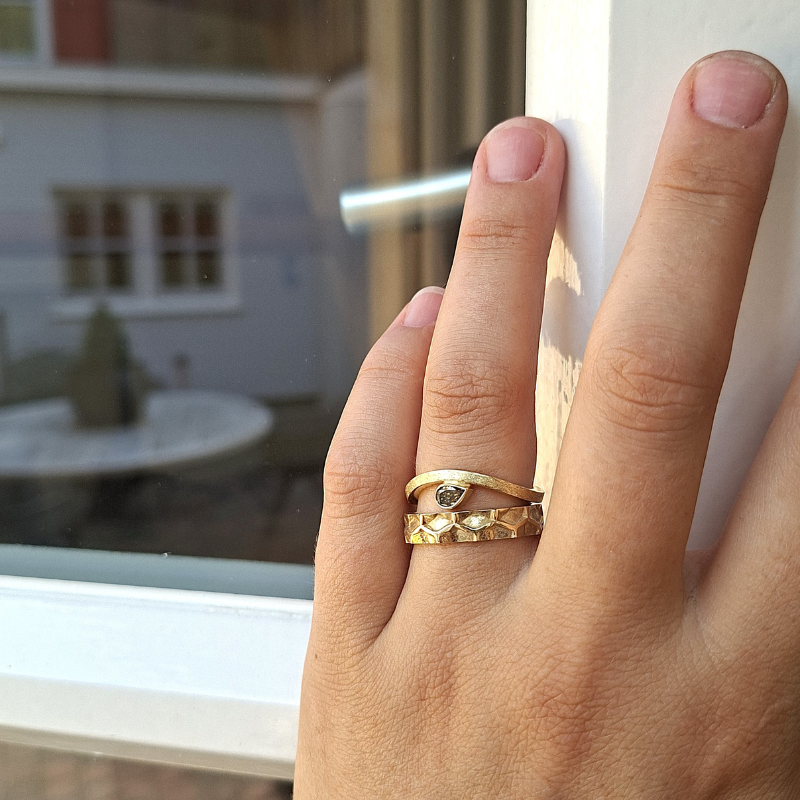 Gouden golvend minimalistische ring met een druppelvormige bruine diamant , als trouwring, aanschuifring of verlovingsring. tijdloos ontwerp door Goudsmederij Goedbloed foto op model met Honey trouwring