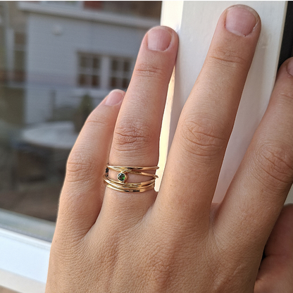 Geelgouden wikkel draadring van vierkant draad met een groene facetgeslepen Toermalijn in een gladde zetkast. Ambachtelijk gemaakt design door Goudsmederij Goedbloed foto op model