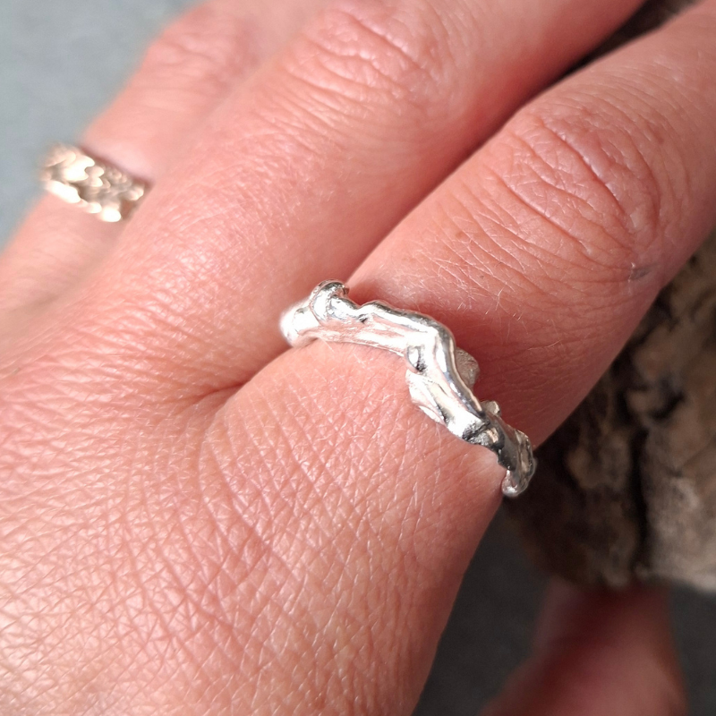Een van zilver gevormd elvenbankje dat speels over de vinger golft als vloeibaar lava - op model-. Handgemaakt en duurzaam ontwerp door Goudsmederij Goedbloed