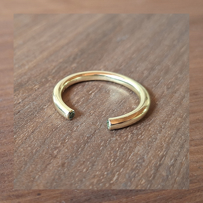 Minimalistische open gouden ring met in de koppen van de ringband doorsnede zijn 2 groene diamanten gezet. Eenvoudig design ring hand gesmeed door Goudsmederij Goedbloed