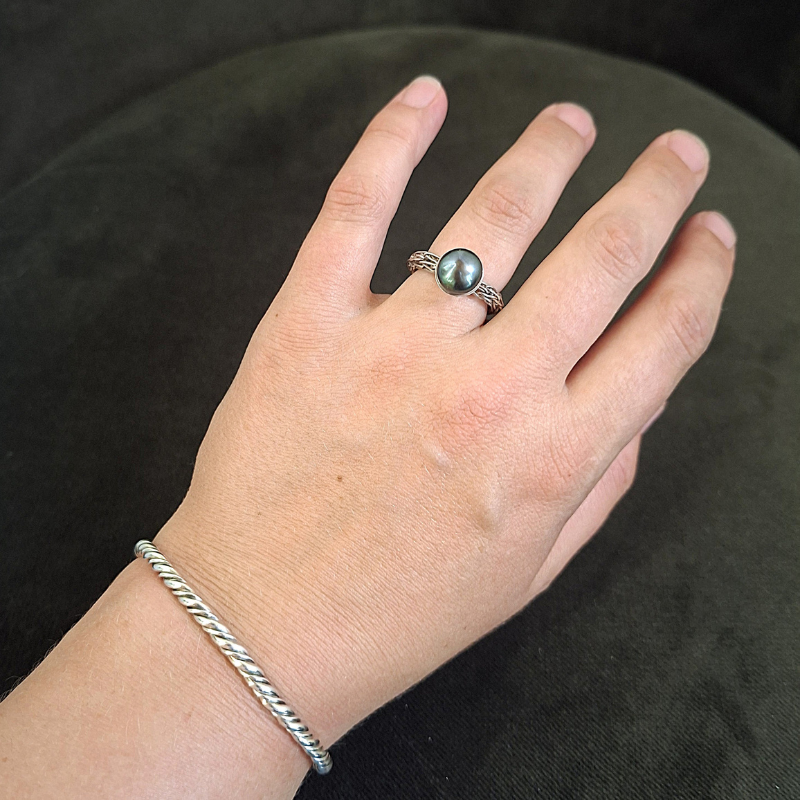 Geweven zilveren ring met een donker groene parel en een getorste viking armband uit de Dragonstail collectie van Goudsmederij Goedbloed foto op model