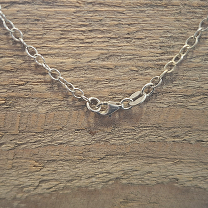 De karabijnsluiting voor het zilveren 925 ankerketting met een symmetrische tussenhanger met krulwerk en op het balanspunt een ophanging met een unieke druppelvormige rozenkwarts. Handgemaakt ontwerp door Goudsmederij Goedbloed