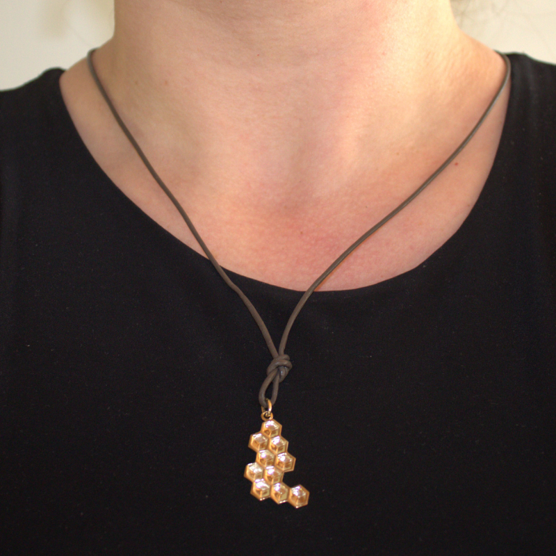 14 karaat geelgouden honingraat hanger uit de Honey collectie, foto op model, organisch en geometisch, textuur hanger, puzzelstukje, asymmetisch handgemaakt door Goudsmederij Goedbloed 