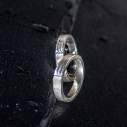 Klassieke trouwringen met een zandgegoten zee textuur als tussenstuk handgemaakt door Goudsmederij Goedbloed