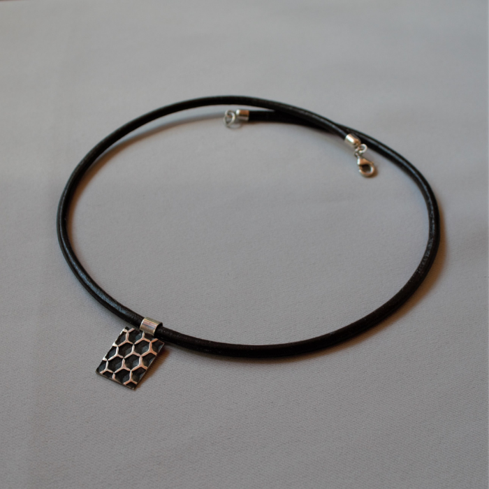 Zilveren tag hanger het Honingraatstructuur aan zwart leren koord. 